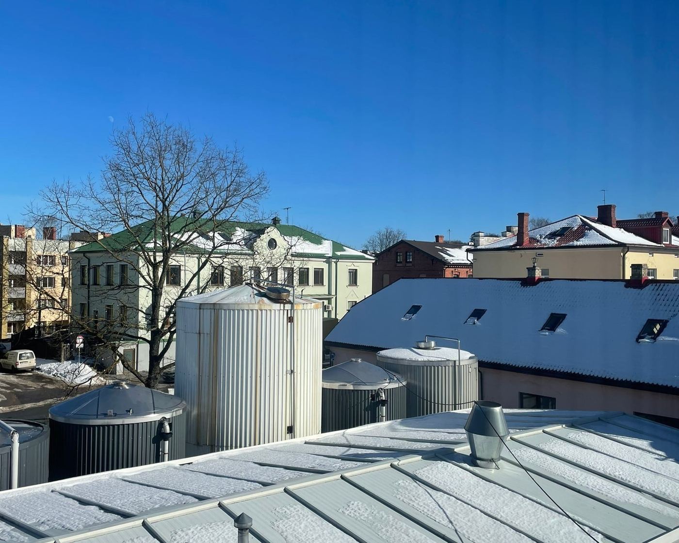Skats no rūpnīcas jumta uz Smilteni, priekšplānā tvertnes.